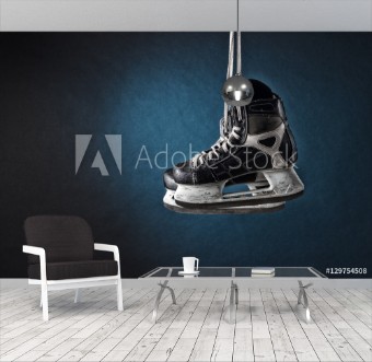 Picture of Mens hockey skates hanging on a dark background